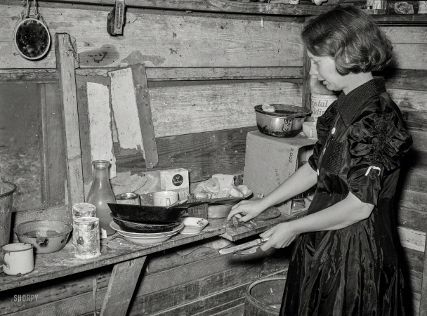 Photo showing: Suppertime. -- February 1939. Corpus Christi, Texas. Wife of war veteran living in shantytown on Nueces Bay.