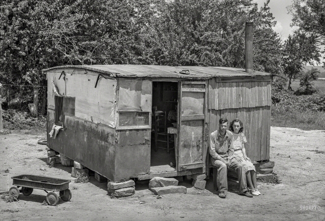 Photo showing: We Ate the Chickens -- June 1939. WPA worker and his wife sitting in front of their shack home ... 
