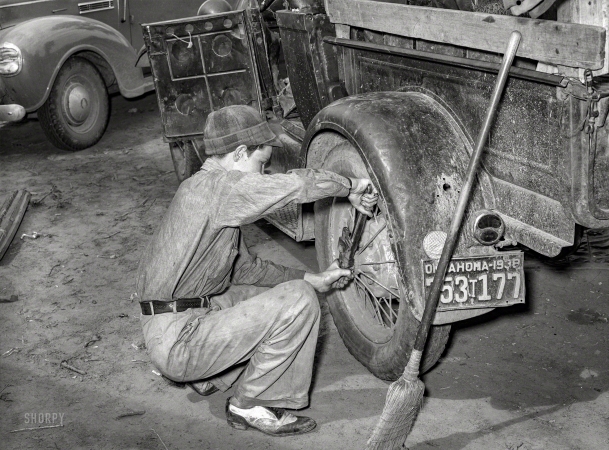 Photo showing: Ready to Roll - -- July 1939. Migrant boy tightening the rear wheel on truck
which will carry his family to California from Muskogee, Oklahoma.
