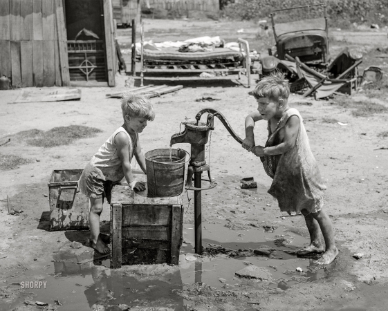Photo showing: Water Boys -- July 1939. Oklahoma City. Children of Mays Avenue camp pumping
water from 30-foot well which supplies about a dozen families.