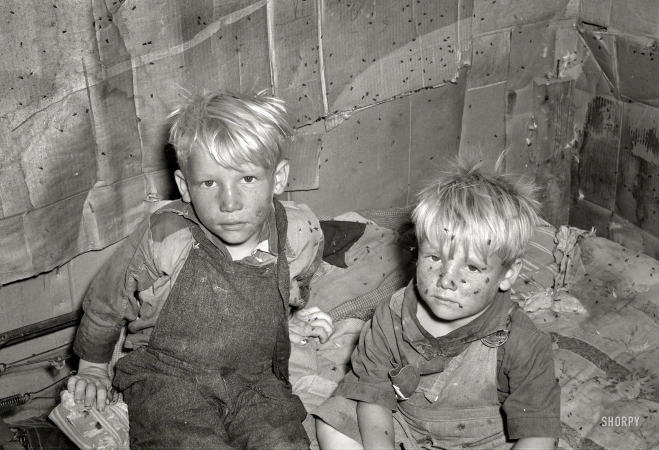 Photo showing: Lad of the Flies -- July 1939. Oklahoma City, Oklahoma. Children of May Avenue camp family in small shack used as sleeping quarters.