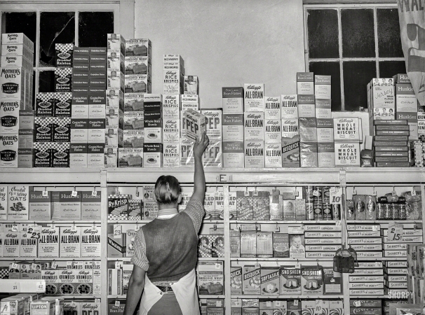 Photo showing: Cereal Stocker -- November 1939. Placing packaged goods on display rack. Retail grocery in San Angelo, Texas.