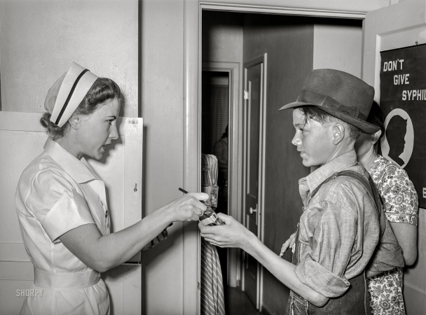 Photo showing: Nurses Orders -- May 1940. Nurse giving instructions to son of migratory laborer
as to how to take medicine. Agua Fria migratory labor camp, Arizona.