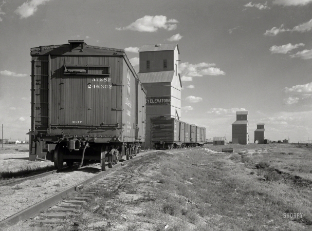Photo showing: Grain to Go -- August 1936. Grain elevators at Dumas, Texas.