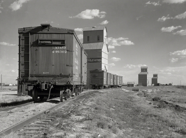 Photo showing: Grain to Go -- August 1936. Grain elevators at Dumas, Texas.