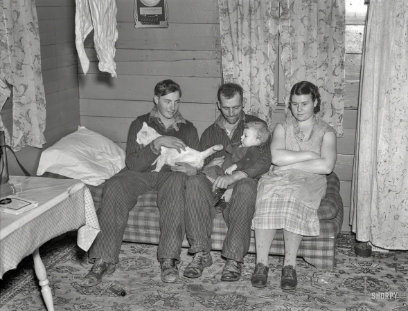 Photo showing: Family Farmers -- December 1936. William Helmke, wife, baby, and brother live in one-room shack on 90-acre farm near Dickens, Iowa.