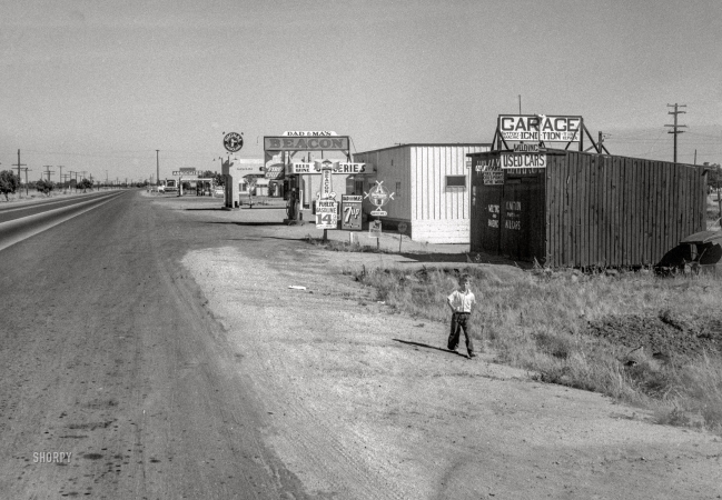 Photo showing: Highway City -- May 1939. Migrant agricultural workers in California. Garage between Tulare and Fresno along U.S. 99 at Highway City.
