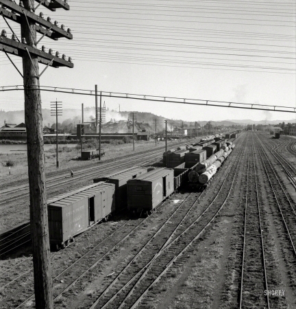 Photo showing: Smoke and Wreckage -- August 1939. Centralia, Washington state. Railroad yard, looking down from highway bridge.
Disaster to the town: The one remaining lumber mill burned down a week before. Note smoke and wreckage.