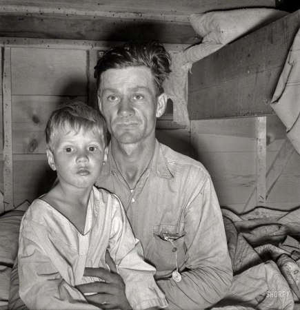 Photo showing: Migrant Father -- October 1939. He brought his family to the West in a homemade trailer from Texas five
months ago. Boy sick. Father has work now in potato field. Merrill, Klamath County, Oregon.