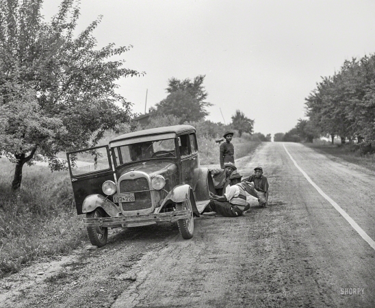 Photo showing: Pit Stop -- July 1940. Migrant fruit workers from Louisiana fixing flat tire along the road. Berrien County, Michigan.