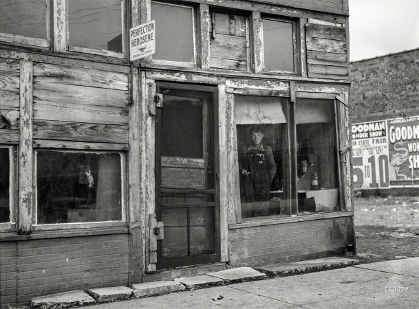 Photo showing: Perfection Kerosene -- January 1939. Abandoned store in which coal miner on relief lives. Zeigler, Illinois.