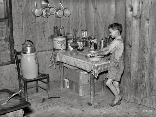 Photo showing: Lard of the Flies -- May 1938. Southeast Missouri Farms. Son of sharecropper washing hands.