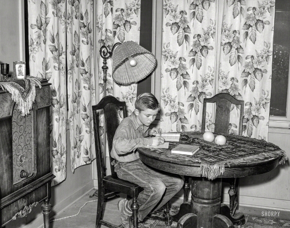 Photo showing: Studious Schmidt -- November 1940. Son of Mr. Schmidt, member of Mineral King cooperative farm, doing his homework. Tulare County, California.
