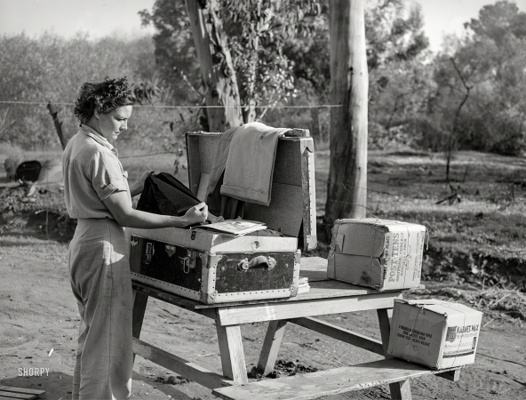 Photo showing: No Picnic -- December 1940. Carpenter's wife unpacking a trunk at tent camp for defense workers in Mission Valley, California.