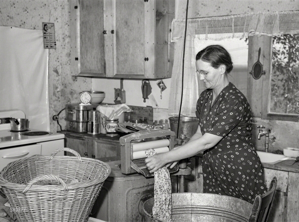Photo showing: The Busy Kitchen -- May 1941. Mrs. E.E. Botner wringing laundry. Malheur County, Oregon.
