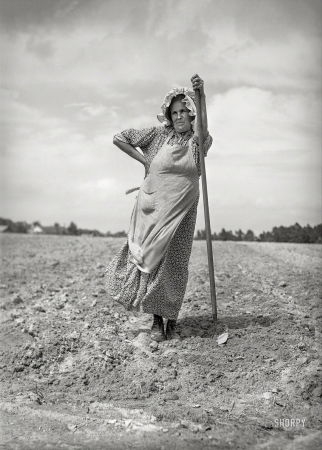 Photo showing: Earth Mother -- June 1940. This woman and her daughter are helping their neighbors plant their tobacco field.
The bonnet is homemade. On U.S. 15, about five miles northeast of Durham, North Carolina.