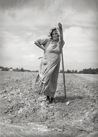 Photo showing: Earth Mother -- June 1940. This woman and her daughter are helping their neighbors plant their tobacco field.
The bonnet is homemade. On U.S. 15, about five miles northeast of Durham, North Carolina.
