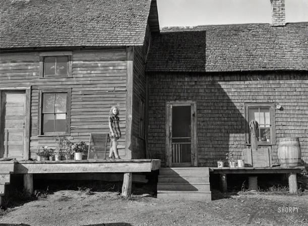 Photo showing: The Potato Farmers Daughter -- October 1940. The daughter of Mr. Dave Labbee, French-Canadian
potato farmer, outside their house near Wallagrass, Maine.