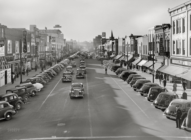 Photo showing: Fayetteville at Five -- March 1941. Traffic on the main street of Fayetteville, North Carolina,
at about five o'clock, when the workers start coming out of Fort Bragg.