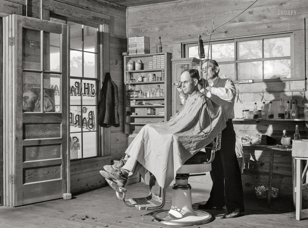 Photo showing: Country Barber -- April 1941. Mr. J.H. Parham, barber and notary public, in his shop in Centralhatchee, Heard County, Georgia.