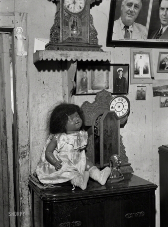 Photo showing: Household Saints -- December 1941. Charlotte Amalie, Saint Thomas Island, Virgin Islands. A colored doll in one of the houses in a slum area.