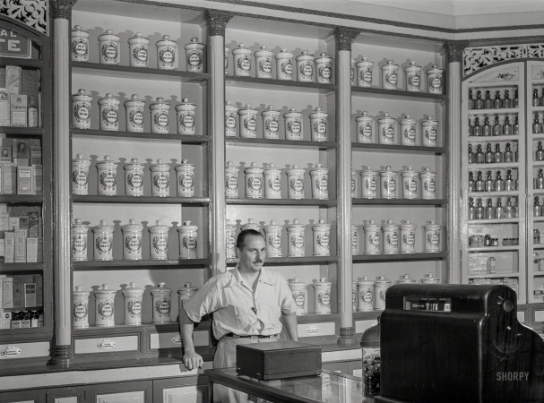 Photo showing:  La Farmacia -- January 1942. Lares, Puerto Rico. In an apothecary store.