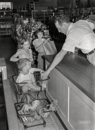 Photo showing: Errand Boy -- September 1938. Children of Greenbelt, Maryland, family buying groceries in cooperative store.