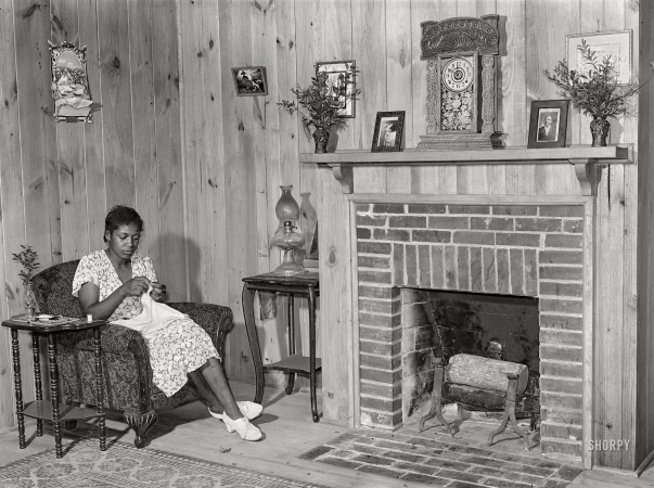 Photo showing: Knotty but Nice -- June 1939. Daughter of Frederick Oliver, tenant purchase client,
sewing in the living room of new home. Summerton, South Carolina.