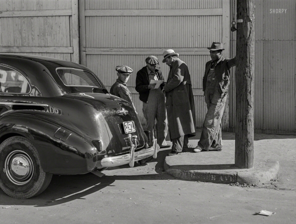 Photo showing: Harvest Time -- November 1939. Farmers looking at their checks outside
tobacco warehouse after auction sales. Durham, North Carolina.