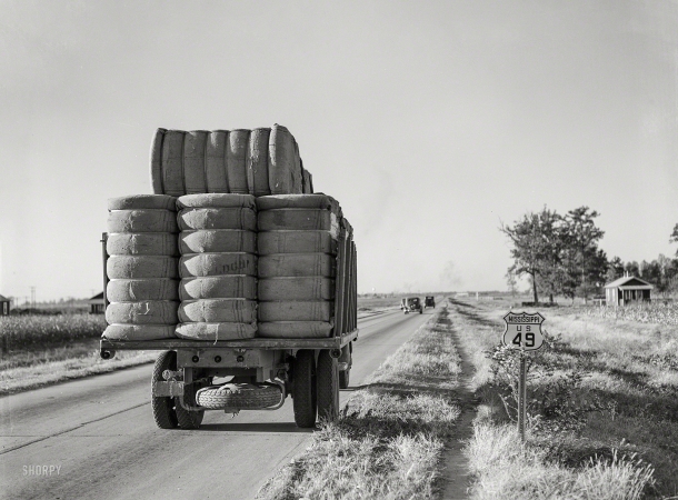 Photo showing: Route Forty-Nine -- November 1939. Truck with bales of cotton from Hopson Planting Co. gin going to warehouse near Clarksdale, Mississippi Delta.
