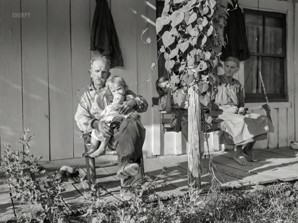 Photo showing: Baby Doll. -- September 1940. Mountaineer with neighbor and her grandchildren
on front porch of their home up Frozen Creek. Breathitt County, Kentucky.