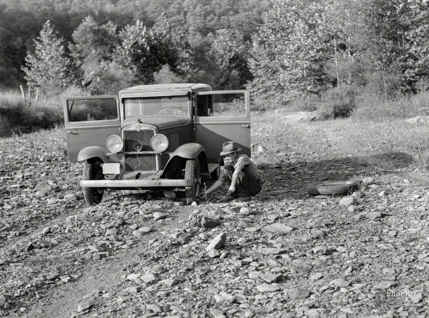 Photo showing: Rocky Road. -- September 1940. Breathitt County, Kentucky. School superintendent
changing tire in streambed. South Fork of the Kentucky River.