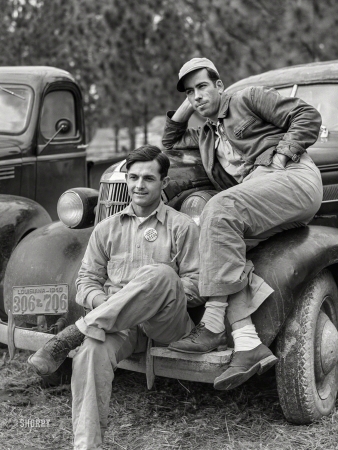 Photo showing: Bumper Buddies -- December 1940. Camp Livingston, Alexandria, Louisiana. Construction workers from
Monroe sitting on car in front of their shacks before leaving for evening shift.