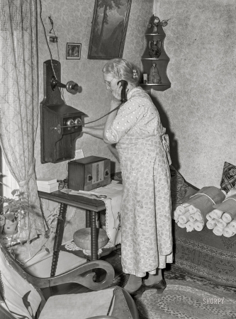 Photo showing: Crank Call -- April 1940. Lady signaling operator on old-style telephone. Scranton, Iowa.