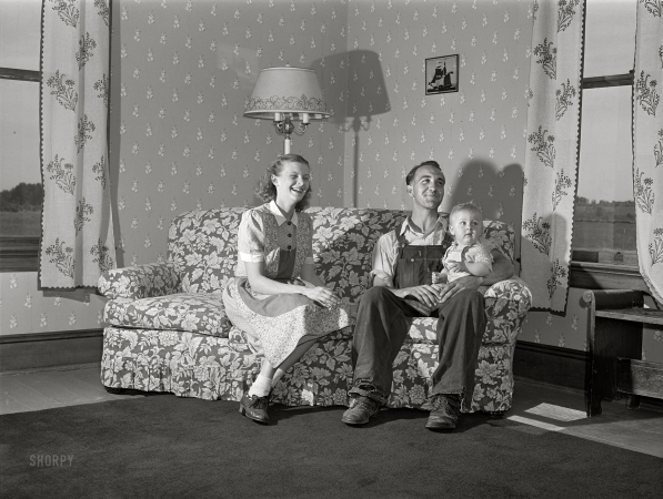 Photo showing: The Happy Homemaker. -- July 1940. Door County, Wisconsin. Farm Security Administration rehabilitation borrower
and family. The wife made the drapes, the chair covers, and papered the wall herself.