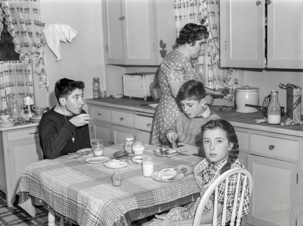 Photo showing: Milk and Cookies -- November 1940. Aberdeen, South Dakota. Mrs. L.M. Schulstad and children in the kitchen.