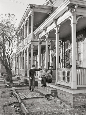 Photo showing: Porch Patrol -- March 1941. Defense workers in front of rooming houses. Norfolk, Virginia.
