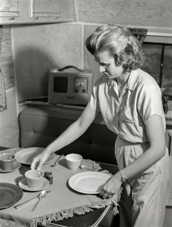 Photo showing: Home Plate -- June 1941. Wife of defense worker setting table for
dinner in trailer home. Trailer camp at Erie, Pennsylvania.