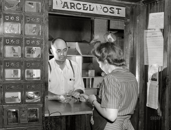 Photo showing: Parcel Post -- July 1941. Buying stamps in post office. Siren, Wisconsin.