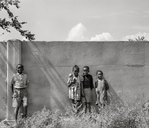 Photo showing: The Wall -- Negro children standing in front of half-mile concrete wall, Detroit, Michigan. This wall was built in
August 1941 to separate the Negro section from a white housing development going up on the other side.