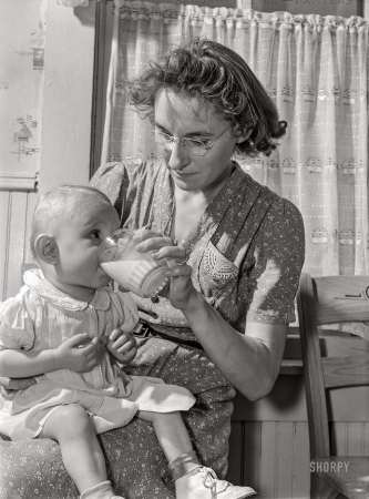 Photo showing: Little Sipper -- May 1942. Lancaster County, Nebraska. Mrs. Pierce, wife of FSA borrower, giving her daughter a glass of milk.