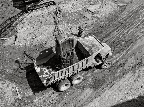 Photo showing: Dam Dump -- June 1942. Shasta Dam, Shasta County, California. Steam shovel dumps dirt into dump truck.
