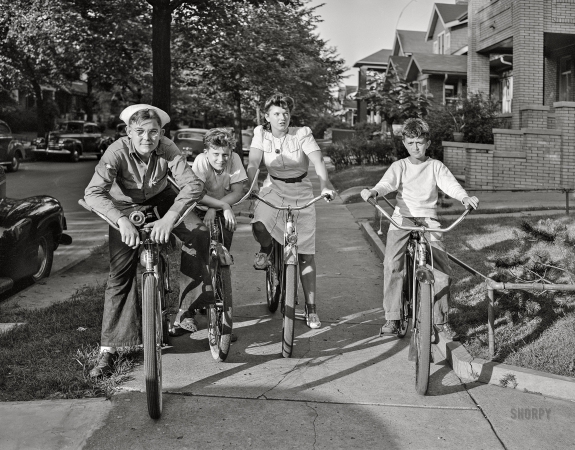 Photo showing: Sidewalk Squadron -- July 1942. Detroit, Michigan. Boys and a girl on bicycles.