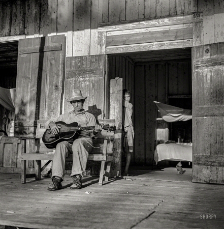 Photo showing: Guitar Lesson -- August 1940. Farmer playing guitar on the porch in the evening. Near Natchitoches, Louisiana.