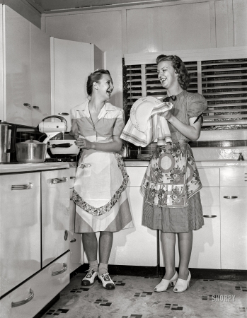 Photo showing: The Happy Homemakers -- July 1942. Dunklin County, Missouri. Daughters of a U.S. Rural Electrification
Administration (REA) cooperative member using electric appliances in their farm kitchen. 