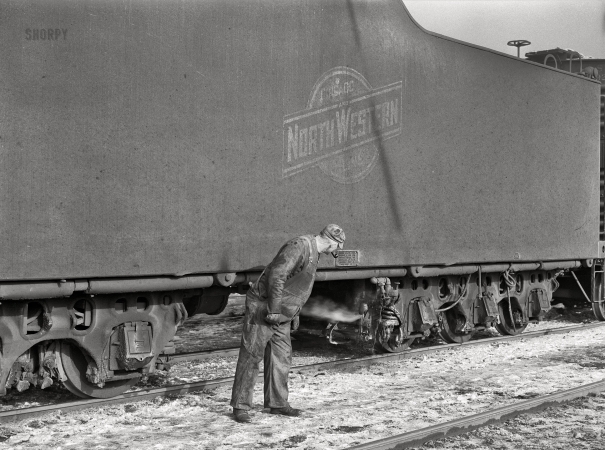 Photo showing: Checkin Tender -- December 1942. Chicago, Illinois. Engineer taking a last look at the tender before going out on the road.