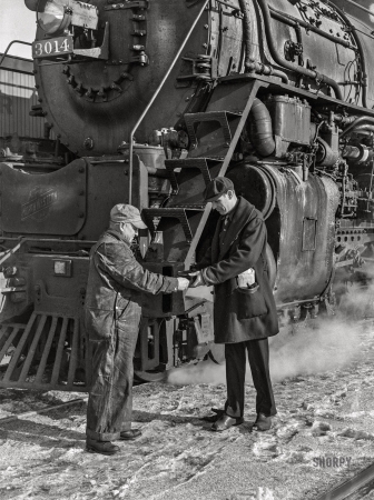 Photo showing: See You in Iowa -- January 1943. Conductor handling engineer copy of train orders before
a Chicago and North Western freight pulls out of Chicago for Clinton, Iowa.