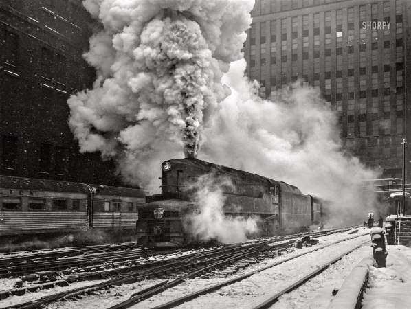 Photo showing: Manhattan Limited -- February 1943. Chicago, Illinois. One of the Pennsylvania Railroad's
giant '6100' class engines pulling out of Union Station on the 'Manhattan Limited' run.