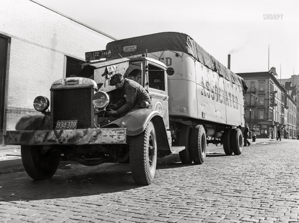 Photo showing: Truck Check -- February 1943. New York. Associated Transport terminal on 23rd Street. Mechanic checking motor of a transport truck.