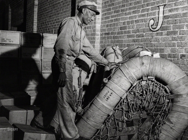 Photo showing: Raft Warehouse -- March 1943. New Orleans. Loading a rubber raft onto a truck at the Associated Transport terminal.
